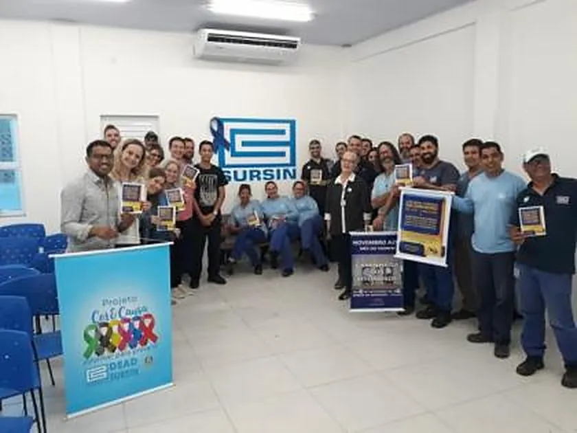 Funcionários da Corsan seguram folhetos ao lado de cartaz do Novembro Azul em ação do INPRÓS