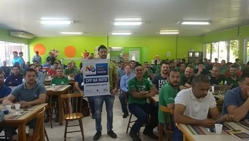 Trabalhadores da Unifertil reunidos em um salão com mesas durante ação do INPRÓS