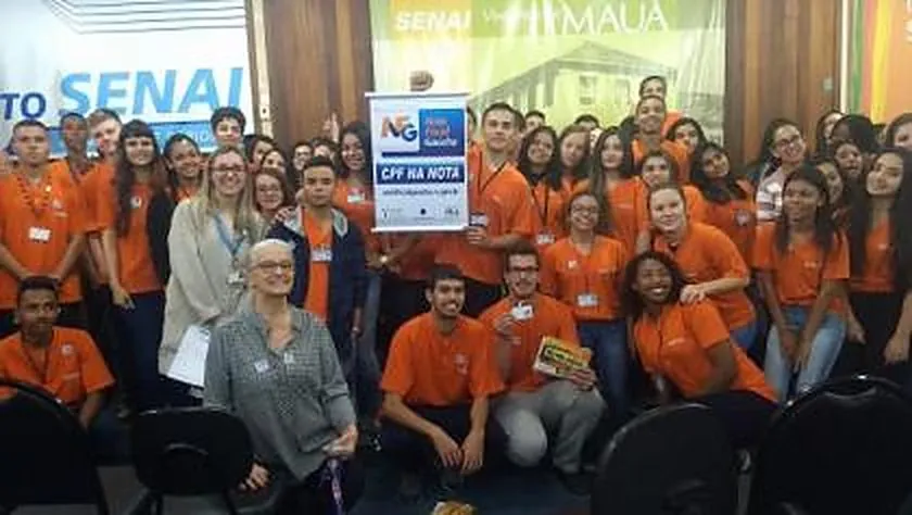 Jovens de uniforme laranja reunidos em ação do INPRÓS no SENAI, com a faixa da Nota Fiscal Gaúcha